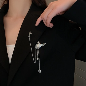 Detail of silver flying horse brooch with crystal wings and long metal tassel chains