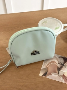 Mint green semicircular PU leather mini lipstick pouch with zipper on wood table
