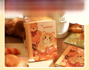 Close-up detail of A7 portable notebook with cute bear and cat illustrations on cover
