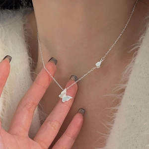 Detail of 925 sterling silver butterfly choker worn on neck with white enamel charms
