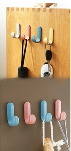 Detail showing colorful J-shaped adhesive wall hooks used for hanging keys and umbrellas
