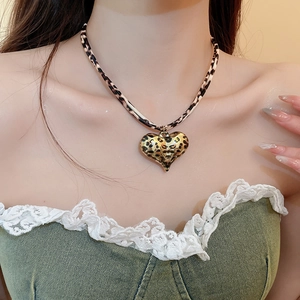 Detailed close-up of a stylish leopard print heart pendant necklace worn on a model's neck