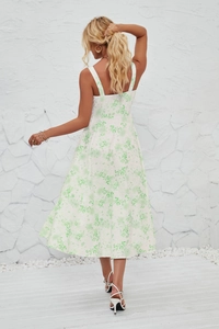 Rear view of floral print midi sundress with thin straps against a textured wall