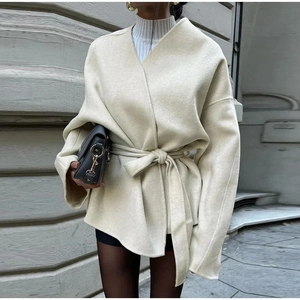 Detail of a minimalist cream white belted wool jacket with deep V-neck and fabric texture