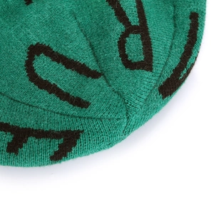 Macro shot of dark green jacquard knit beanie with black bold letters texture