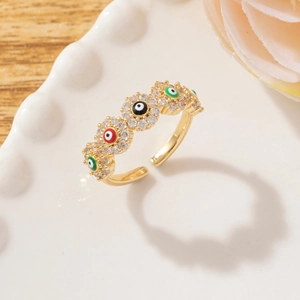 Macro detail of gold adjustable ring featuring colorful enamel evil eyes and pavé zircons