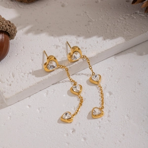 Golden heart zircon tassel drop earrings displayed on white textured stone background