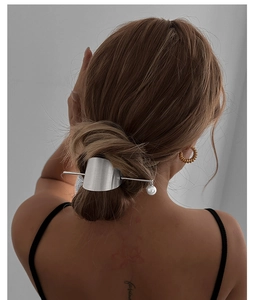 Silver metal hair pin with white pearl pendant worn in a sleek hair bun by a model