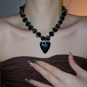 Close-up of marble pattern beaded necklace with heart pendant and gold accents on a model