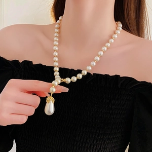 Detail of drop pearl necklace with rhinestones on a model wearing a black dress