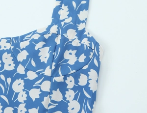Détail de l'encolure à fleurs bleues et des coutures de la robe fendue ajustée