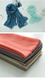 Detailed view of colorful solid cotton linen scarves stacked and styled with accessories