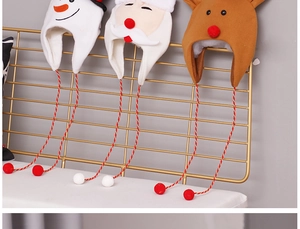 Three plush Christmas hats featuring snowman, Santa, and reindeer hanging on a gold rack