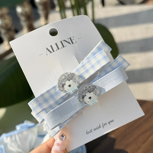 Close-up of light blue checkered hair clips featuring cute poodle dog head decorations