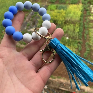 Detail of blue and marble silicone bead wristlet with gold clasp and leather tassel