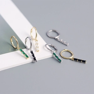 Close-up of S925 silver hoop earrings with rectangular emerald and clear zircon pendants