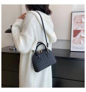 Rear view of a black quilted shell bag with gold hardware worn by a model in casual style