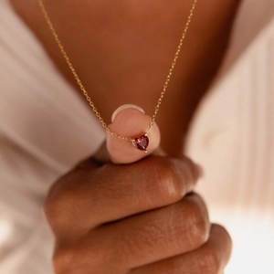 Close-up of heart-shaped red gemstone necklace in 18k gold-plated finish worn on neck