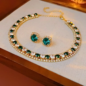 Close-up of gold-plated necklace set with green round gems and sparkling crystals