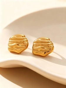 Detailed close-up of 18k gold-plated hammered texture earrings on a ceramic tray