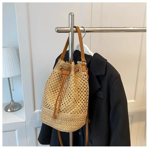 Detail of khaki straw bucket bag featuring brown leather drawstring and shoulder strap