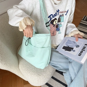 Dettaglio della borsa a tracolla in nylon verde menta con coulisse e tasche frontali