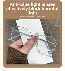 Detail einer runden Metallbrille mit Blaulichtfilter, die in der Hand gehalten wird