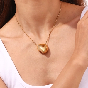 Polished gold heart pendant on thin O-chain necklace worn by a fashion model