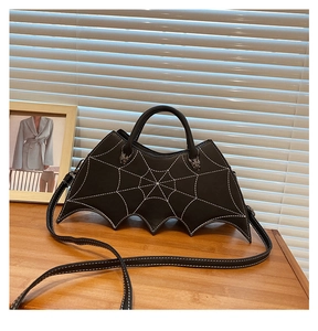 Detail of black PU leather bat-shaped handbag with white spiderweb embroidery and metal charms