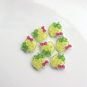 Flat lay of seven strawberry resin charms for DIY crafts with pink bows and green details