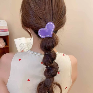 Détail d'un accessoire de cheveux en acrylique violet en forme de cœur sur une queue
