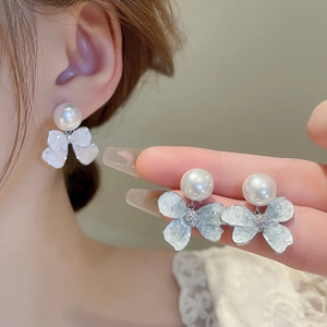 Detailed macro view of the bow-shaped crystal petal base and round white pearl earring