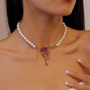 Close-up of pearl necklace featuring a pink crystal flower pendant with metal tassels
