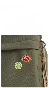 Detail of red rose and daisy enamel pins set attached to a green canvas bag