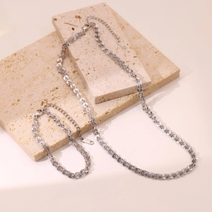 Minimalist silver stainless steel chain necklace and bracelet jewelry set on stone base