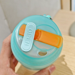 Detail of light blue water bottle lid with orange sliding lock and embossed OPEN button