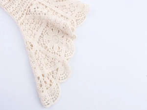 Detailed macro view of beige crochet lace fabric with intricate floral cutout patterns
