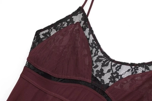 Detail of burgundy textured fabric with black floral lace trim and thin straps