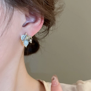 Detail showing a leaf-shaped stud earring with blue enamel and sparkling zircon accents
