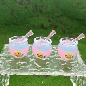 Detailed view of three mini resin honey jars with pink sticks on glass over grass