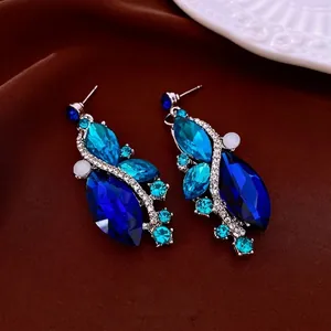 Elegant silver drop earrings with blue marquise crystals on brown silk background