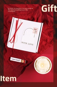 Exquisite scented candle gift box with white rose candle and red ribbon on deep red fabric