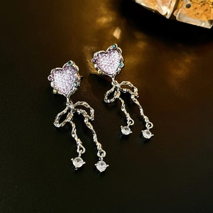 Detail of silver bow earrings with purple heart crystals and zircon tassels