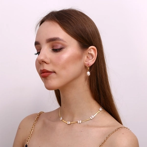 Detail of 18K gold butterfly choker and pearl earrings worn by a fashion model