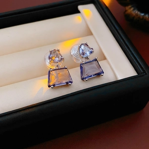 Macro shot of geometric purple trapezoid earrings with zircon droplets in jewelry box