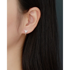 Close-up of a silver butterfly earring with small diamonds on a model ear
