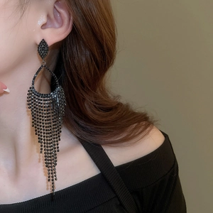 Close-up of black teardrop rhinestone tassel earrings worn on a female model