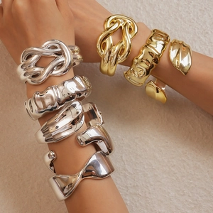 Close-up of stacked gold and silver geometric twisted acrylic bangles with wavy texture