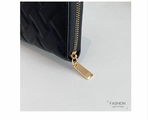 Macro shot of high-quality black woven leather purse with shiny gold zipper detail