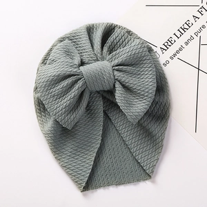 Detail of grey-green baby turban hat featuring a large bow and soft waffle knit texture